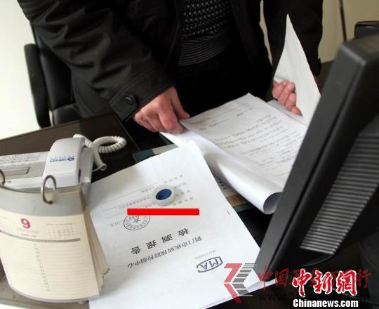 湖北省荊門市衛生監督局工作人員向記者介紹肯德基湖北荊門店食品吃出異物調查情況，圖中紅線處為肯德基漢堡里面吃出的塑料蓋。　吳奇勇 攝